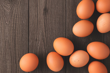 Flat lay ten brown chicken eggs on the surface of a vintage wooden rustic table with copy space