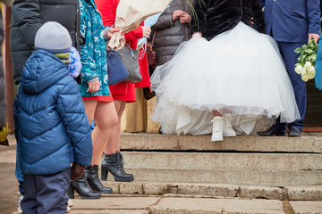 Feet of the bride and groom outdoors. A girl in white shoes and a man in black shoes before the wedding ceremony outside