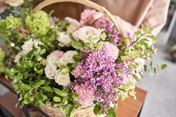 Fototapeta na wymiar Floral shop concept . Florist woman creates flower arrangement in a wicker basket. Beautiful bouquet of mixed flowers. Handsome fresh bunch. Flowers delivery.