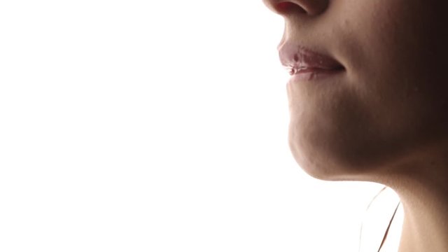The girl sexually licks her lips with her tongue. Close up on a white isolated background. Shiny wet lips.