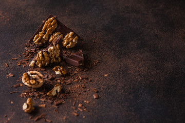 Pieces of chocolate with walnut on a dark brown background