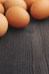 Vertically oriented photo of fresh brown chicken eggs on an old vintage rustic background with copy space.
