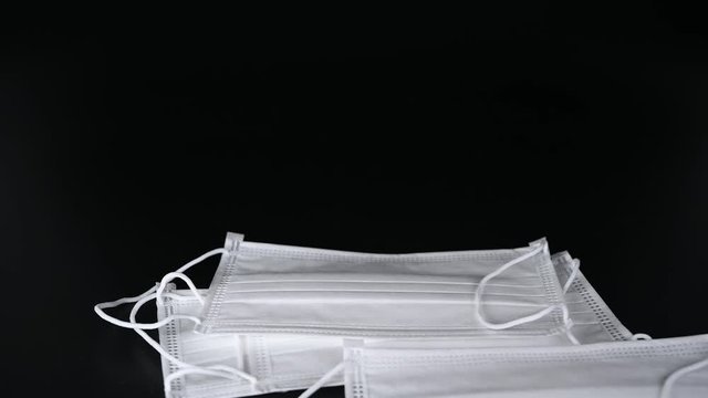 Medical disposable masks stacked on a black background.
