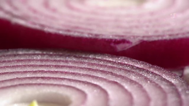 Sliced red onion rings rotating in 4K. Closeup top view of healthy food background with vegetable of rich vitamin
