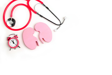 Human kidney symbol with stethoscope and alarm clock on white background.