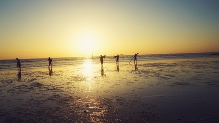 Fototapeta na wymiar Tan Thanh beach, Go Cong district, Tien Giang province, Vietnam - Feb 2020: Photo of fishing village people using homemade tools to catch fish in sea at sunrise