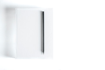 Mockup of closed blank square book and black pencil at colored textured paper background