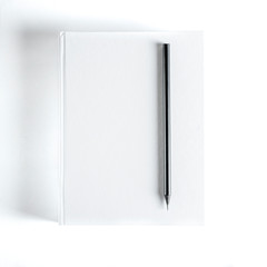 Mockup of closed blank square book and black pencil at colored textured paper background