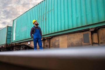 Portrait of shipping worker checking cargo containers at train station ready to be dispatch to the...