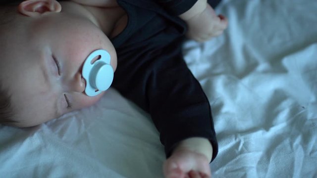 kid in black clothes with pacifier in mouth sleep