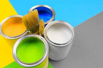 Metal paint cans and paint brushes on multicolor background. Top view. Copy space. - Image