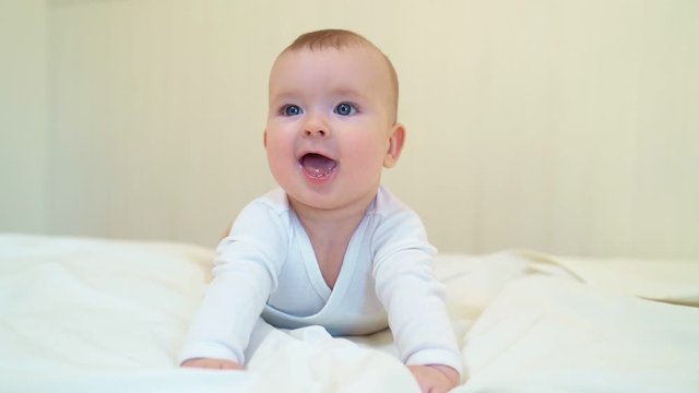 baby in white clothes lying on paunch on white bed