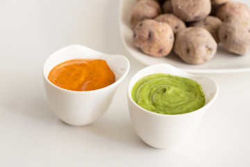 Canary Islands pdish Papas Arrugadas ( wrinkly potatoes) with Mojo picon (Red hot sauce) and  Mojo verde ( Green sauce)  on restaurant table