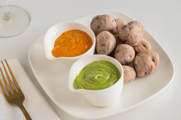 Canary Islands pdish Papas Arrugadas ( wrinkly potatoes) with Mojo picon (Red hot sauce) and  Mojo verde ( Green sauce)  on restaurant table