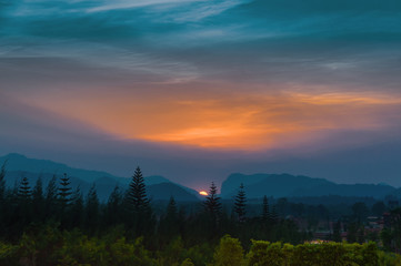 Landscape of beautiful colorful dramatic sunset sky, twilight sky over shilhulette mountains and pine forest.