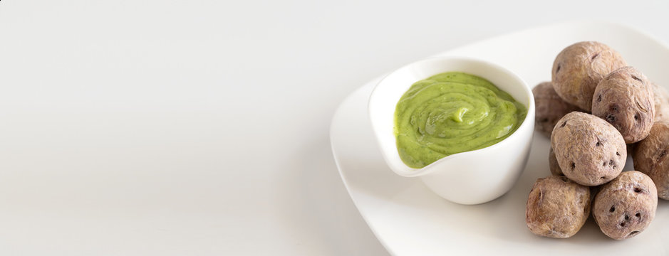 Typical Canary Islands dish,Papas Arrugadas ( wrinkly potatoes) with Mojo Verde ( Green sauce)on restaurant table. Large image for banner.Copy space