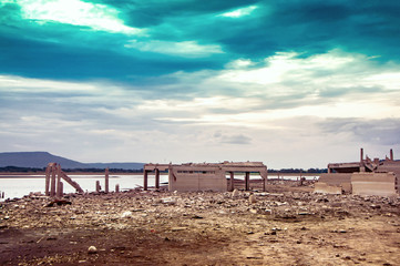 Climate change and drought land, Water crisis from climate change. drought concept. Low level of water of Pasak Chonlasit Dam of Thailand reveal dirty land and debris of old underwater building.