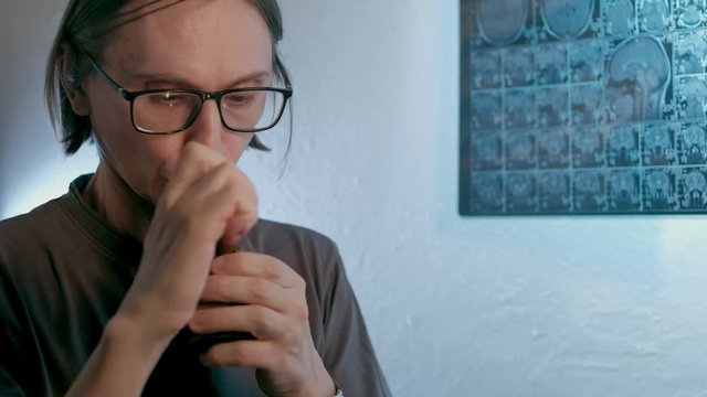 a sick man smokes cannabis against a background MRI image on which his head is. Looped. 4k