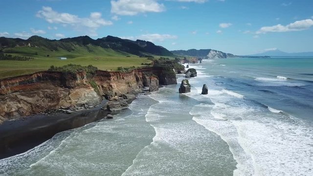 Aerial, drone shot, flying over the ocean, waves crashing into the cliffs, 4K, at the Three Sisters in New Zealand