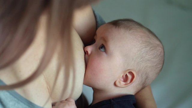 Woman breastfeeding newborn baby. Mother breastfeeding newborn boy. Concept breast feeding. Baby eating mother's milk. Young woman nursing and feeding baby. Concept of lactation infant.