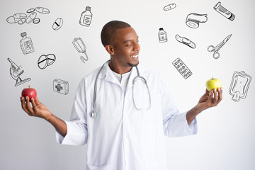 Doctor comparing apples with hand drawn medical sketches. Healthy nutrition concept. Isolated front closeup view with medicine icons on background.