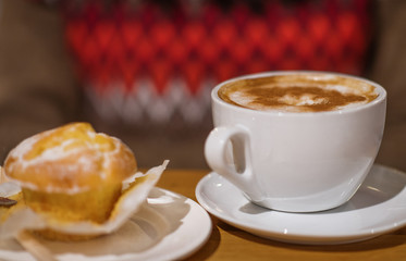 Cap of coffee with muffin/cake on the table in the cafe