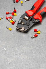 Fototapeta premium Tool for crimping stranded electrical wires. Crimping tool for an electrician or Builder on a grey concrete background