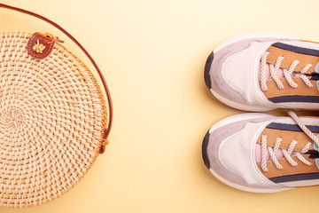 Sneakers and rattan bag on yellow background. Travel concept. Flat lay