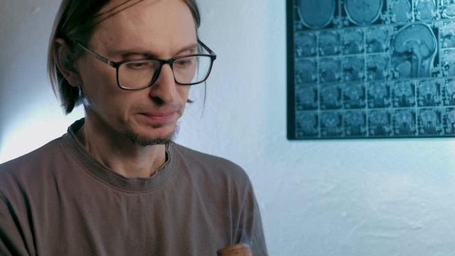 a sick man smokes cannabis against a background MRI image on which his head is. Looped. 4k