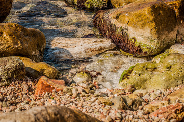 Big rocks and clear seawater at wild beach.