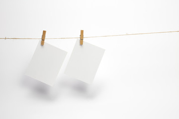 Empty paper frames that hang on a rope with clothespins and isolated on white. Blank cards on rope. Mockup template for memories backdrop, photos, social media etc.
