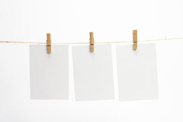 Empty paper frames that hang on a rope with clothespins and on white background with selective focus. Blank cards on rope. Mockup template for memories backdrop, photos, social media etc.