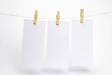 Empty paper frames that hang on a rope with clothespins and on white background with selective focus. Blank flyers on rope. Mockup template for memories backdrop, photos, social media etc.