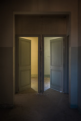 Puertas simétricas abiertas en habitación de casa abandonada.