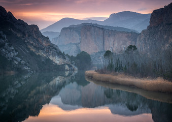 Paisaje al atardecer de montañas reflejadas en el agua del pantano de Sant Llorenç de Montgai (Cataluña, España).