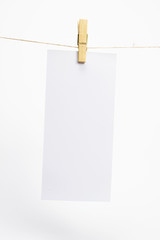 Empty paper that hang on a rope with clothespins and on white background with selective focus. Blank flyer on rope. Mockup template.