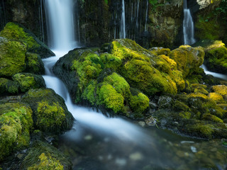 Cascada de agua en arroyo y rocas con musgo verde.
