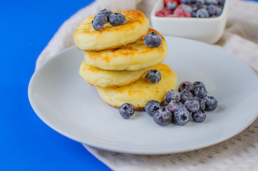 Pancakes with strawberries, raspberries, blueberries on a blue background.