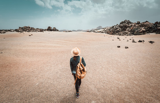 Young woman with backpack walking by the desert enjoying freedom and life, people travel wellbeing concept.	