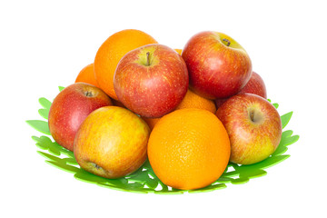Apples and oranges on a green plate isolated on white background