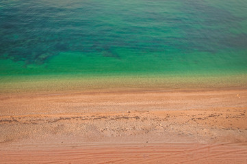 Colorful empty sand beach with emerald clear water