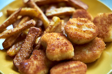 Tasty homemade potato french fries with chiken nuggets on yellow dish
