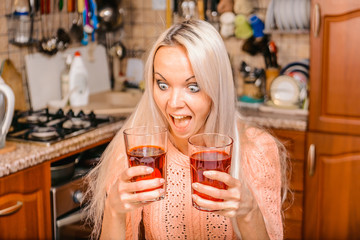 Blonde girl in the kitchen with colored liquids in glasses.