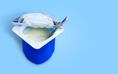 Yogurt, plastic cups and spoon on blue background. Yogurt made from milk fermented by added bacteria, often sweetened and flavored.