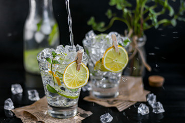 Refreshing summer alcoholic cocktail Margarita with crushed ice, lime and mint for decoration. Vodka splash. On a dark wooden background. On the leaves of the newspaper.