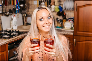 Blonde girl in the kitchen with colored liquids in glasses.