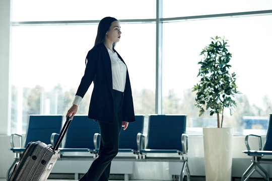 Young asian business woman in airport with trolley bag, waiting for departure