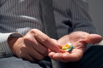 businessman with a pill, hands close view - concept of difficulties, depression, problems, health and stress, risk of modern business