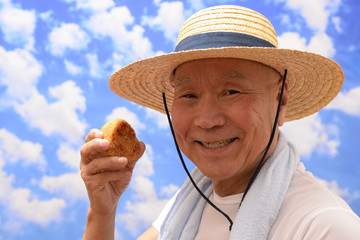Fototapeta premium 青空でおにぎりを食べるシニア