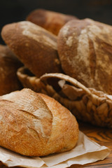 Assortment of baked bread on wooden table background. Bread background, top view of white, black and rye loaves. Healthy food. 